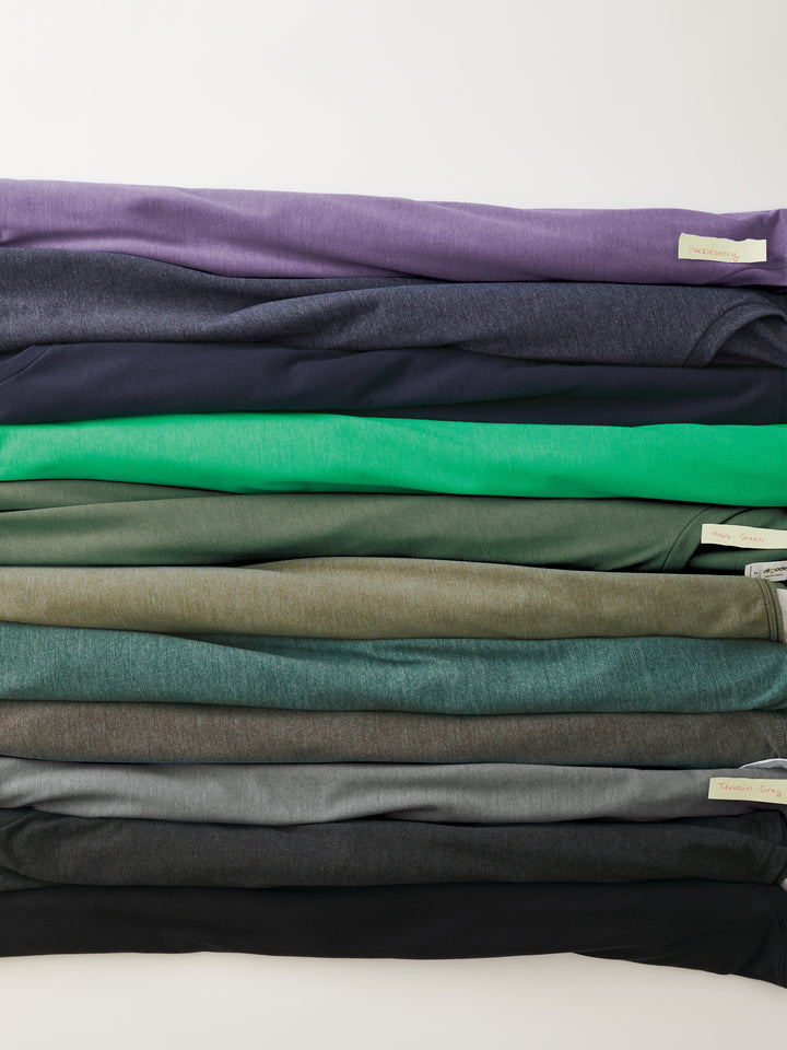 Assorted shades of Custom Allmade Tri-Blend Tees neatly folded. Sustainable and stylish, ideal for custom branding.