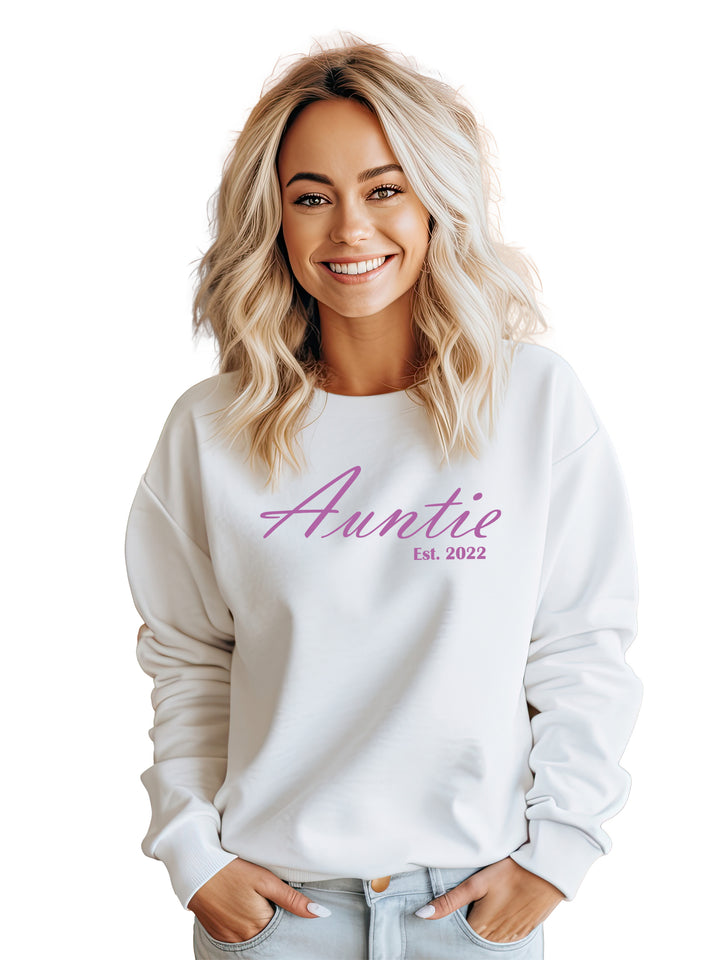 Custom embroidered Auntie sweatshirt in white, worn by a smiling woman. Features 'Auntie, Est. 2022' in pink script. Cozy and stylish gift for aunts.