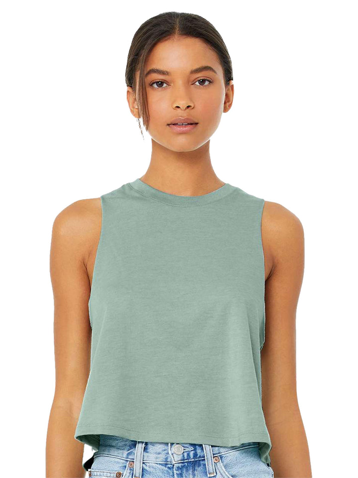Bella + Canvas Women’s Racerback Crop Tank in sage green, featuring a sleeveless, cropped design. Styled with denim for a casual look.