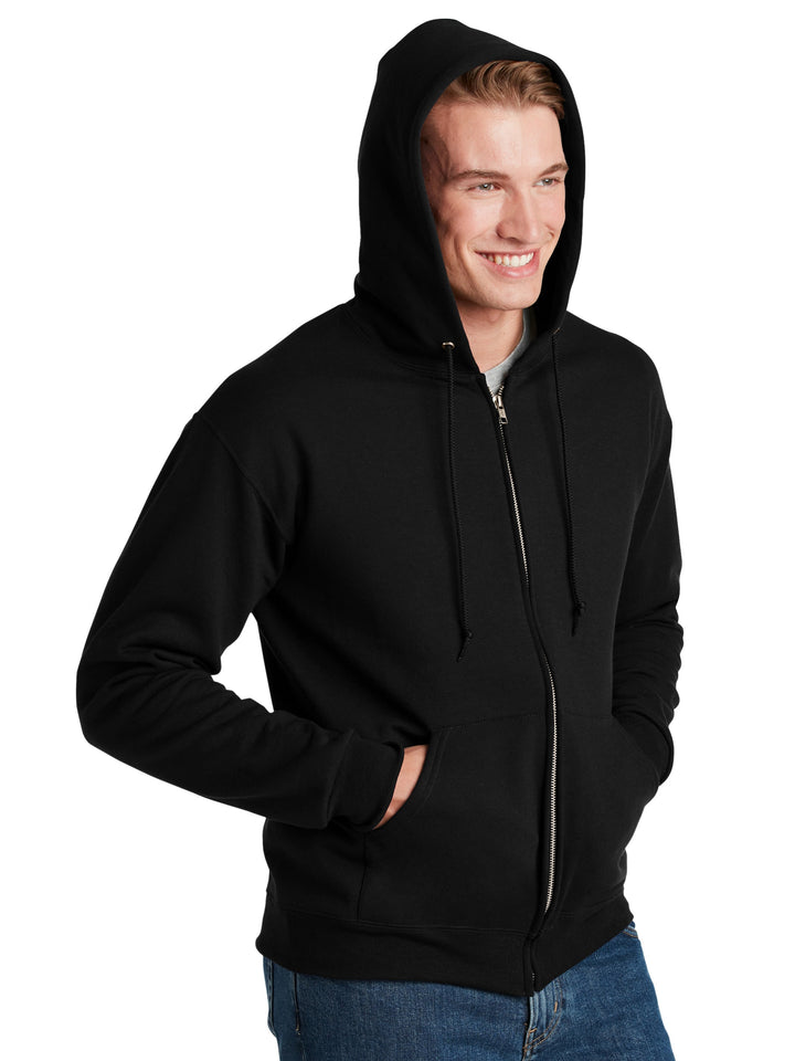 Jerzees Super Sweats Full Zip Hoodie in black, shown with hood up and hands in pockets. A heavyweight, customizable sweatshirt for comfort and warmth.