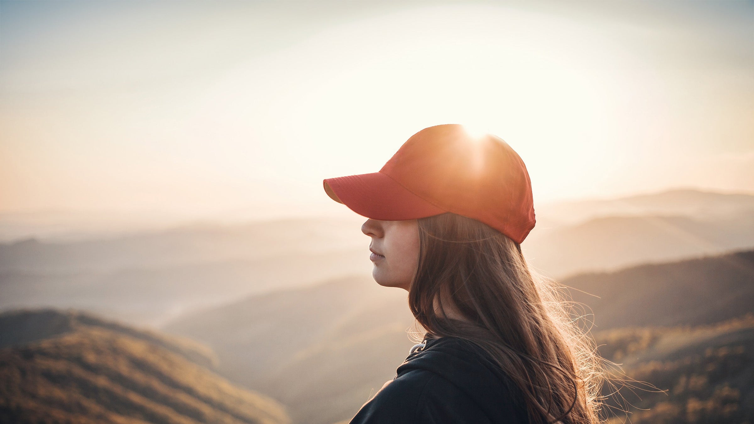 Woman wearing red hat with mountains in background