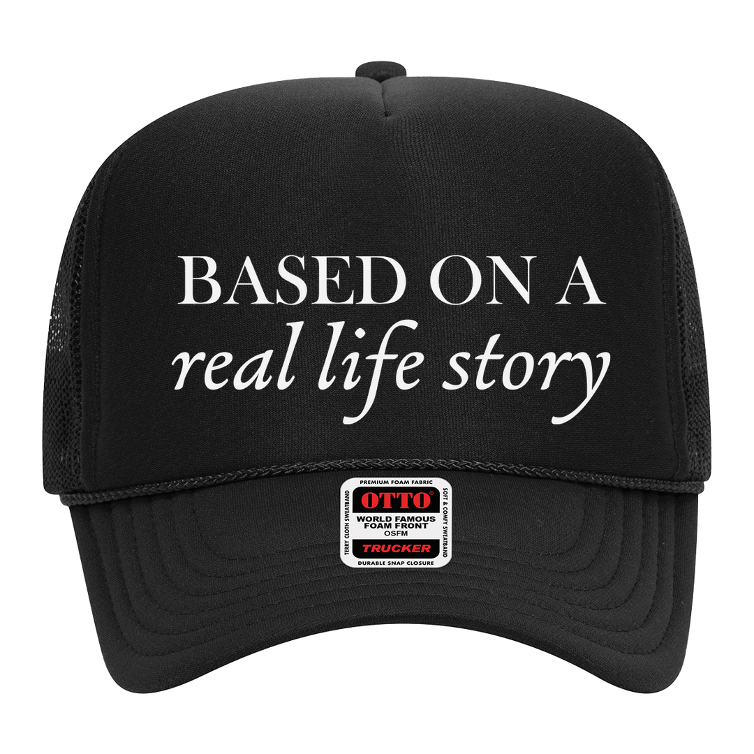 Front view of black foam trucker hat featuring 'Based On A Real Life Story' text in white. Classic mesh back cap with structured fit.