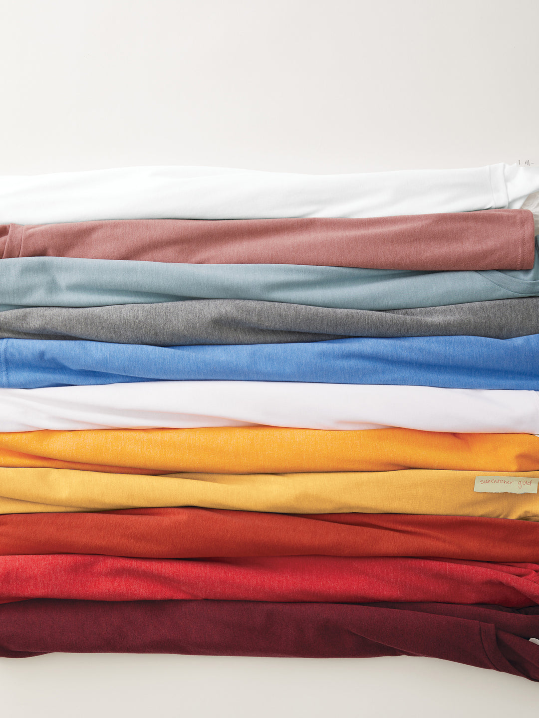 Stack of folded Custom Allmade Tri-Blend Tees in various colors. Soft, eco-friendly fabric perfect for personalized designs.