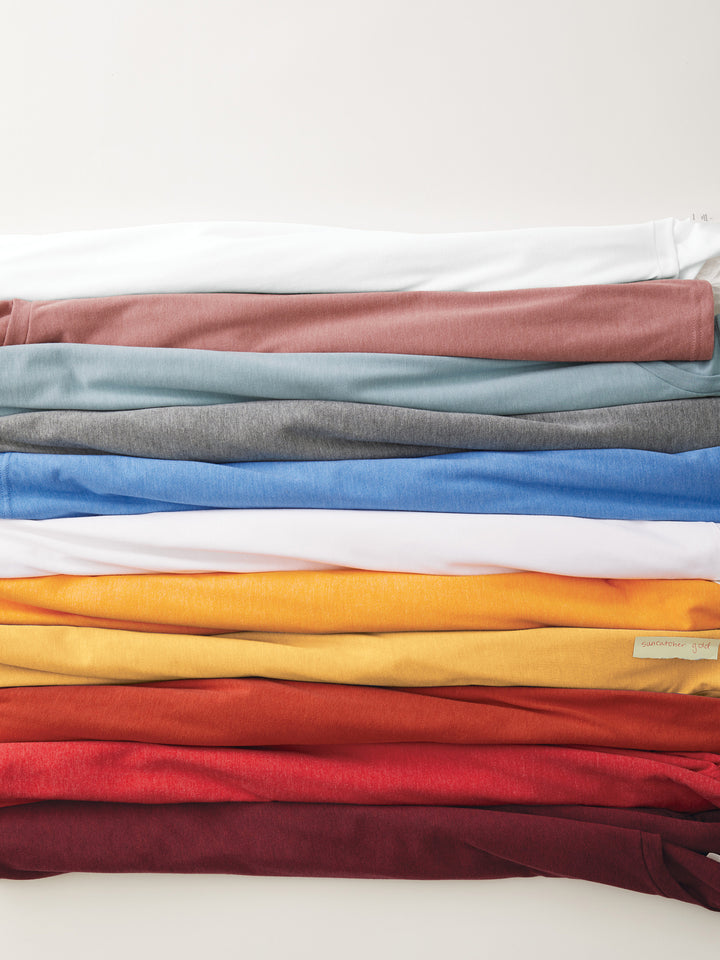 Stack of folded Custom Allmade Tri-Blend Tees in various colors. Soft, eco-friendly fabric perfect for personalized designs.