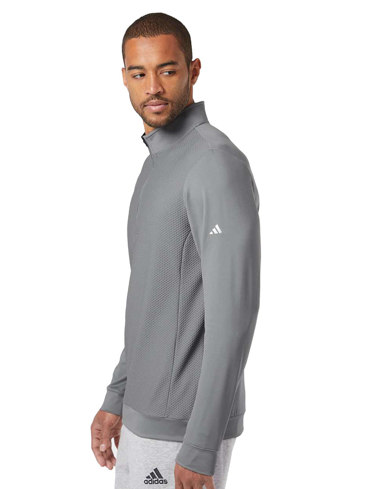 Side view of the gray Adidas Performance Textured 1/4 Zip Sweatshirt. Showcases the Adidas logo on the sleeve and textured fabric.