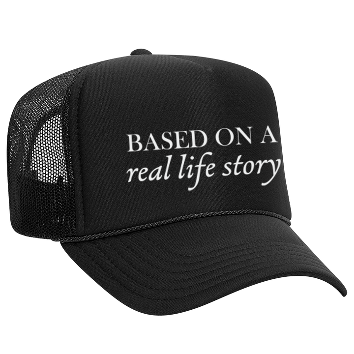 Black foam trucker hat with 'Based On A Real Life Story' text in white. Stylish mesh back cap for casual wear and street fashion.