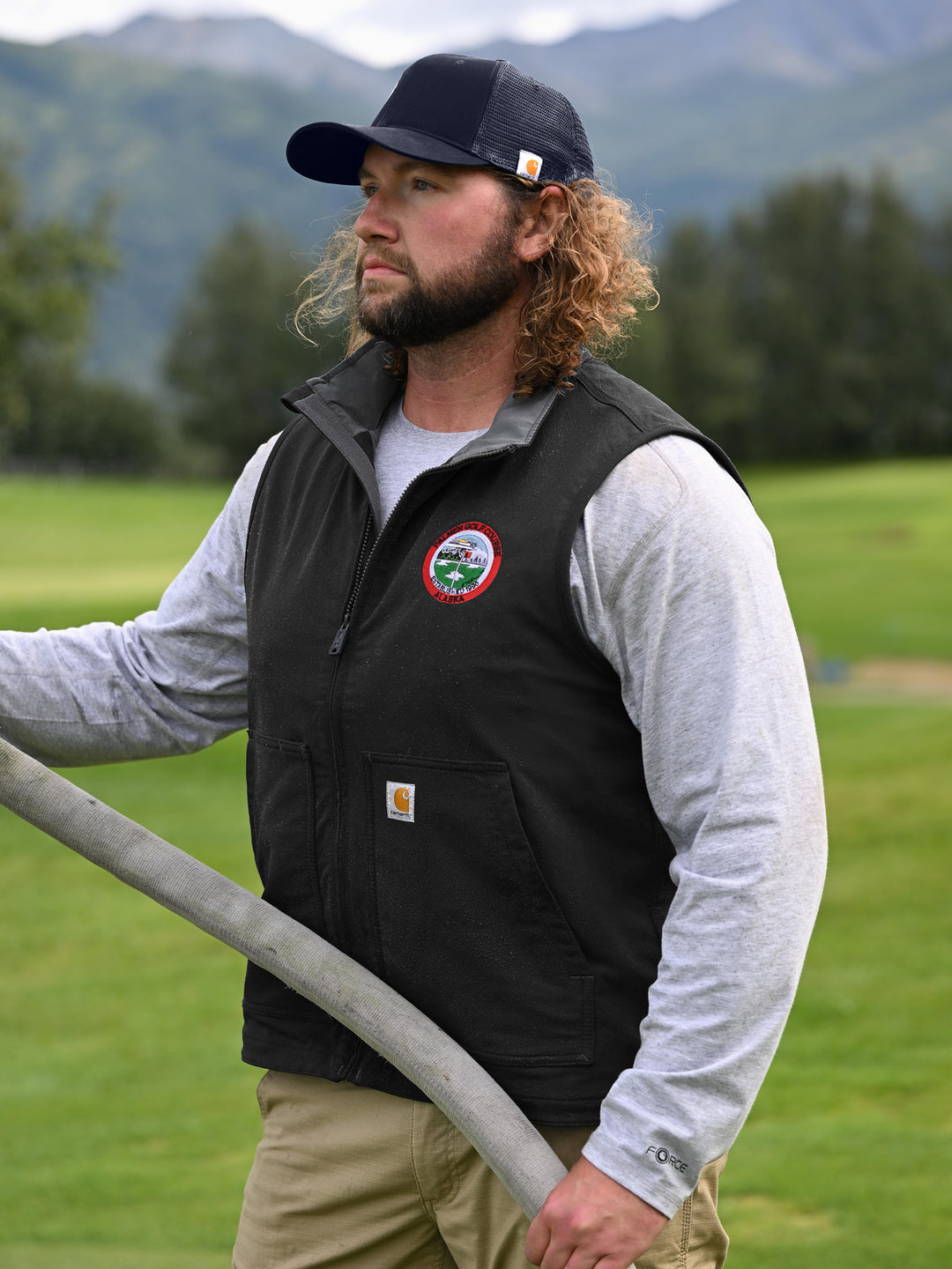 Man wearing navy Custom Carhartt Canvas Mesh Back Cap while working outdoors, highlighting its rugged design and breathable mesh back.